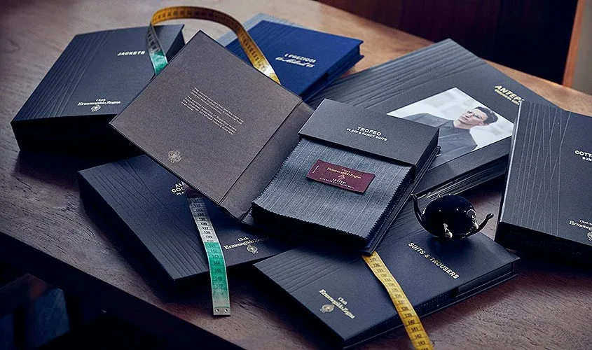 Zegna Trofeo bunch books with grey wool swatches and tape measures on a desk