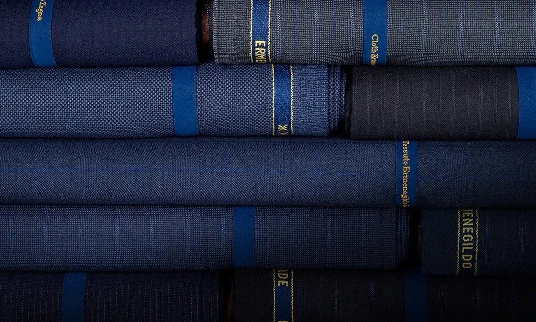 Stacked bolts of Zegna suiting cloth in layered navy and blue weaves