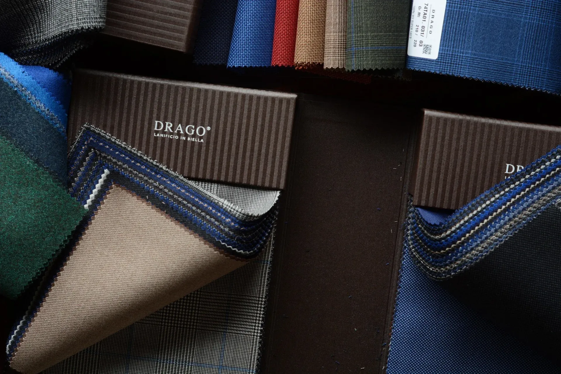 Drago swatch books fanned open in green, brown and bright blue suiting cloths