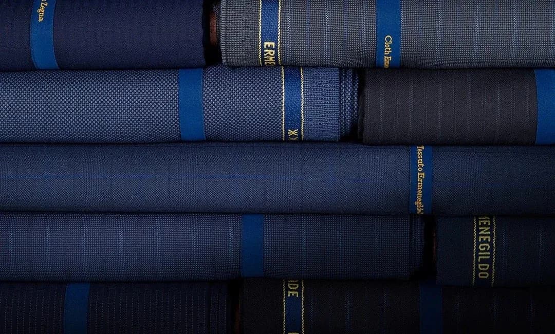 Stacked bolts of Zegna suiting cloth in layered navy and blue weaves